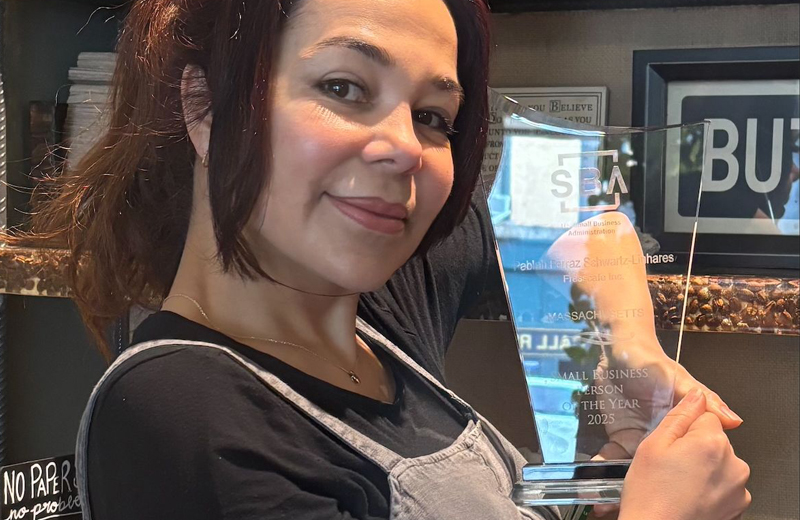 close up of Pablah Schwartz, owner of Fresscafe in Framingham and Natick, Massachusetts-she is holding a glass award from the SBA while standing in the back room of her restaurant